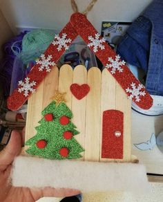 a hand holding a christmas decoration made out of popsicle sticks and wood planks