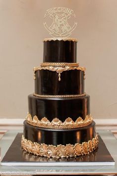 a three tiered black and gold wedding cake