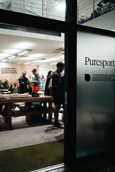 people are gathered around a table in an office building with the doors open to let in light