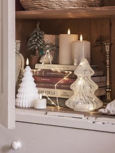 a shelf with candles, books and other christmas decorations on top of eachother