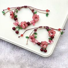 two bracelets made out of beads and flowers on a white plate next to each other