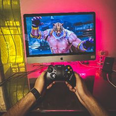 a person holding a game controller in front of a tv with a wrestler on it