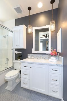 a bathroom with gray walls and white cabinetry is pictured in this image, there are two lights on the ceiling