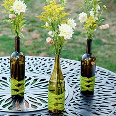 three bottles with flowers in them sitting on a table