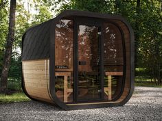 an outdoor sauna is shown in the middle of a gravel area with trees around it