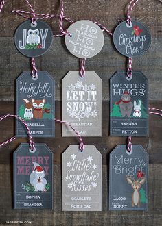 christmas tags are hanging on a wooden wall