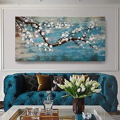 a living room with blue couches and white flowers on the coffee table in front of it