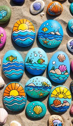 colorful painted rocks on the sand with fish and seashells