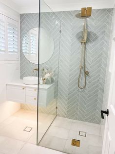 a bathroom with a walk in shower next to a white sink and mirror on the wall