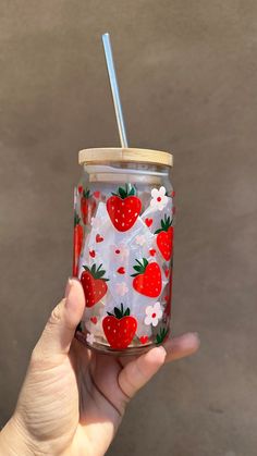 a hand holding a glass with strawberries on it