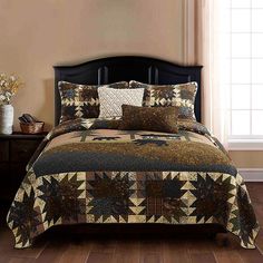 a bed with a brown and black quilt on top of it next to a window