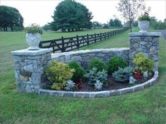 an image of a stone wall with flowers in the middle and plants growing on it