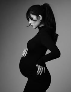 a pregnant woman poses for a black and white photo with her hands on her hips