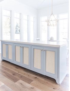 a kitchen with white walls and blue cabinetry in the center, along with hardwood flooring