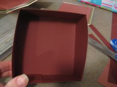 someone is opening up a red box on the table next to some construction paper and scissors