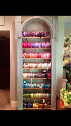 an old cabinet is filled with spools of thread