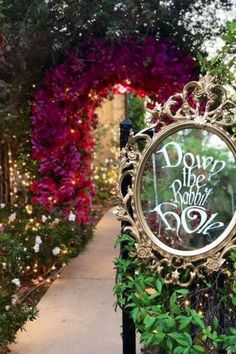 a clock that is sitting in the middle of some bushes and trees with lights behind it