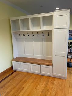 an empty room with white cabinets and wood flooring on the wooden floor, along with several coat hooks