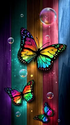 three colorful butterflies flying in the air with bubbles floating around them on a wooden surface