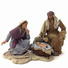 two figurines of jesus and baby jesus sitting on the ground with their hands together