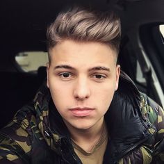 a young man with blonde hair wearing a camouflage jacket