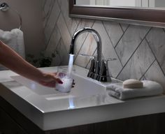 a person is filling a glass with water from the faucet in their bathroom