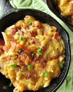 two skillets filled with macaroni and cheese on top of a green cloth