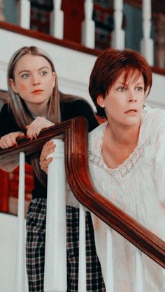 two women are standing on the stairs and one is holding a mirror