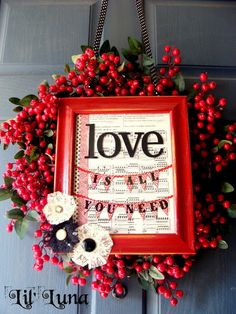 a red frame with the word love hanging from it's side next to flowers