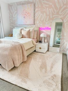 a bedroom decorated in pink and white with a bed, mirror, dresser and nightstand