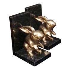 a pair of brass rabbits on black marble bases