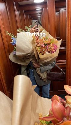 a woman is taking a selfie with her cell phone while holding a bouquet of flowers