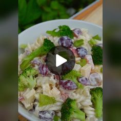 a white bowl filled with pasta and broccoli on top of a wooden table