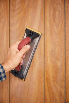 a person using a dust mop to clean a wooden door with a red handle