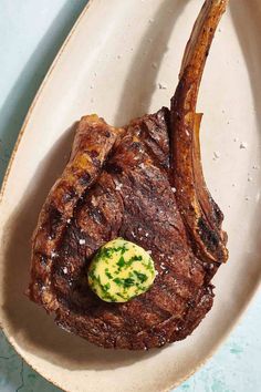 a piece of steak on a white plate with a green garnish in the center