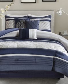 a bed with blue and white comforters in a bedroom next to pictures on the wall