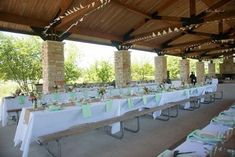 an outdoor dining area with tables and chairs covered in white tablecloths, green napkins and place settings