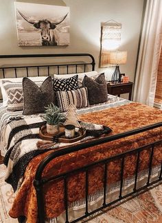 a bed with pillows and blankets on top of it next to a painting hanging above the bed