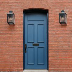 a blue door with two lights on the side of it and a red brick building