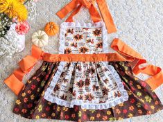 "This beautiful apron is perfect for cooking on Thanksgiving day! Your little helper will enjoy wearing her gobble gobble turkey apron! This apron is made with a cotton fabric featuring a fun turkey print. The top is lined with white cotton fabric and is made with a fun turkey print. The bottom of the apron has two layers and is made with a beautiful fall foliage print fabric. The entire apron is finished with white eyelet lace. The straps are made of a nice orange fabric and are long enough to Kitchen Towels Crafts, Apron Pattern Free, Turkey Print, Apron Sewing, Toddler Apron, American Girl Doll Diy, Foliage Print, Bags Sewing, Towel Dress