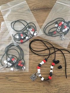 three bags filled with beads and charms on top of a wooden table