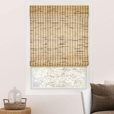 a bamboo roman blind in a living room with pink walls and white trim on the windowsill