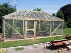 a small greenhouse with a chicken in it's cage next to some wooden benches