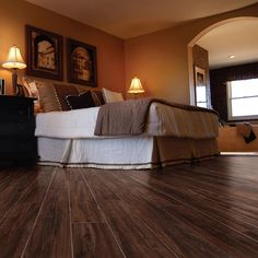 a bedroom with wood flooring and two lamps on the side tables in front of the bed