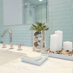 a bathroom sink with candles and rocks in it