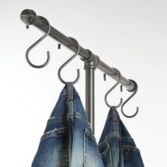 two pairs of jeans hanging on a metal pole with hooks and clothes pins attached to them