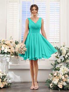 a woman standing in front of flowers wearing a green bridesmaid dress and heels