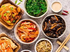 several bowls filled with different types of food and chopsticks next to each other