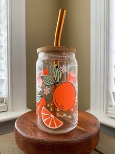 a glass jar with an orange design on it and a straw sticking out of the top