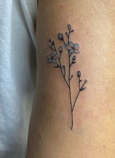 a small flower tattoo on the right side of the arm, with blue flowers growing out of it